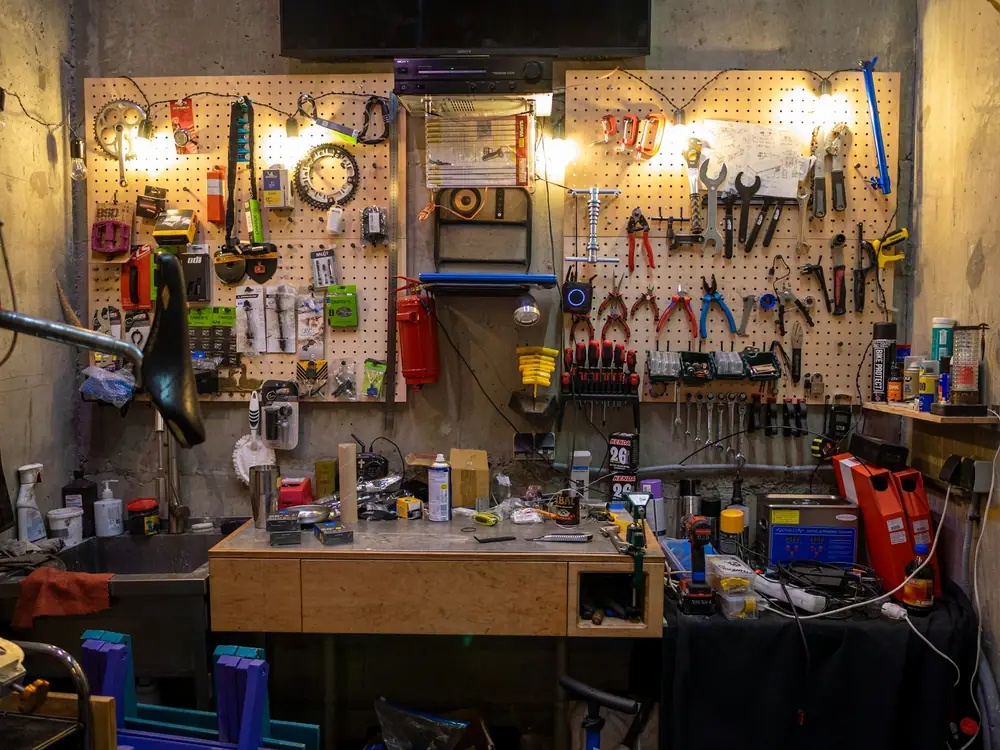 A workshop wall with neatly hung tools above a wooden workbench