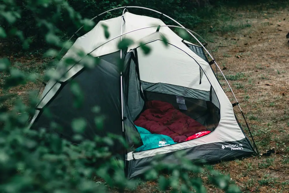 A small dome tent pitched on grass with sleeping bags visible inside