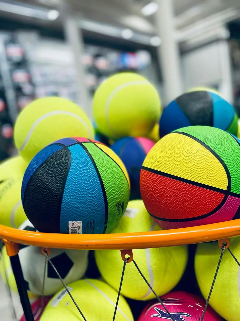 A pile of colorful basketballs and tennis balls in a round bin