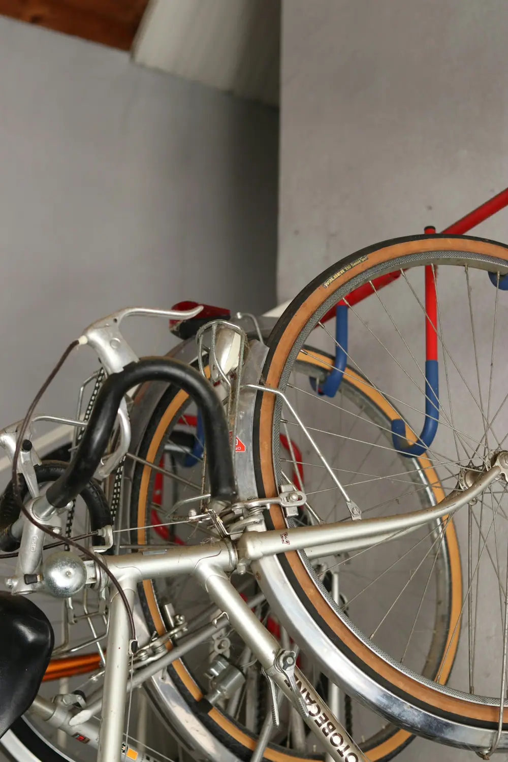 Bicycles hanging on a wall-mounted rack with hooks inside a bright room