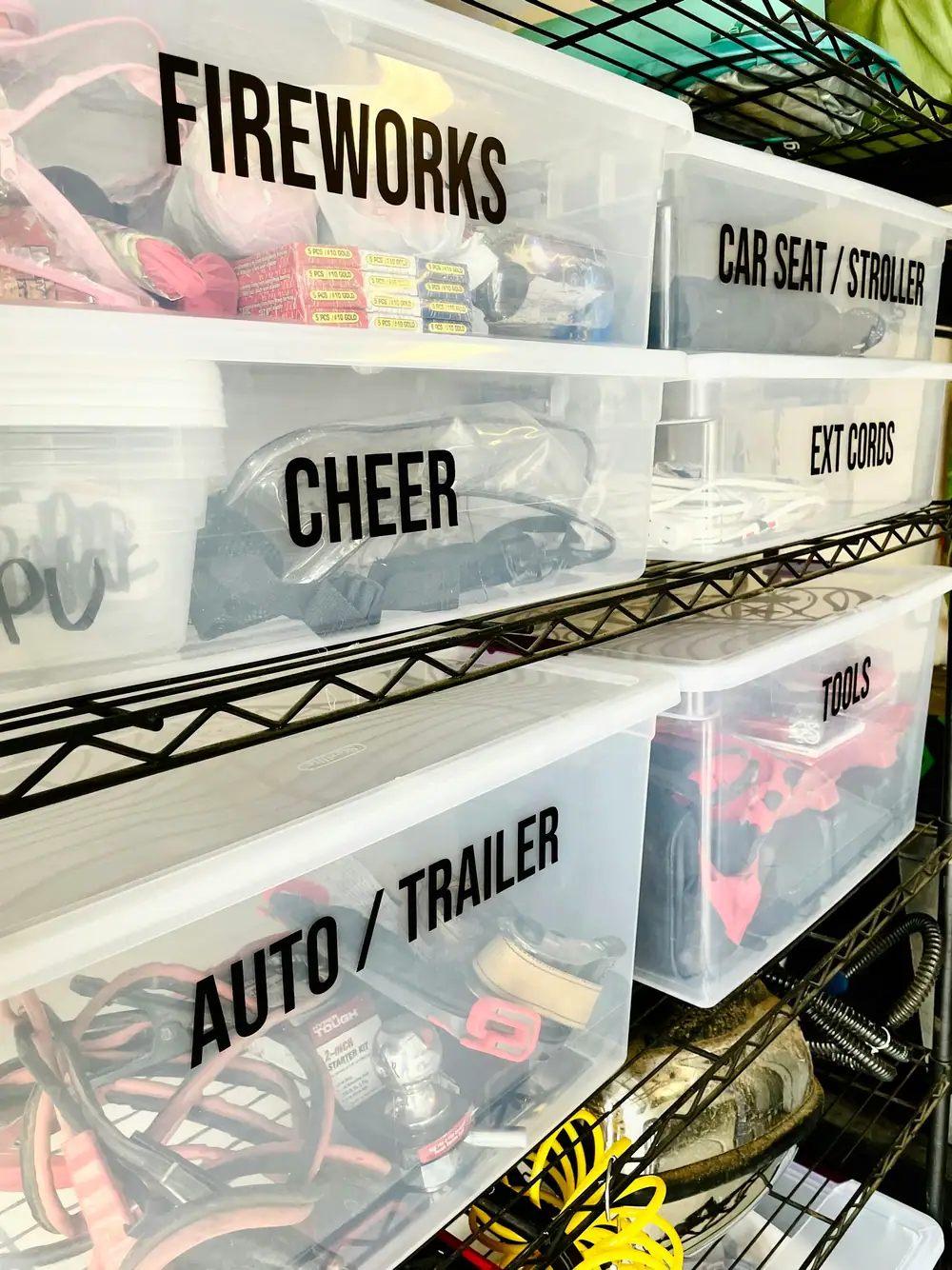 Clear plastic storage bins with bold black labels on a wire shelving unit