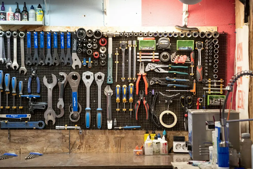 A workshop wall of pegboard with tools and gear hung on hooks above a workbench